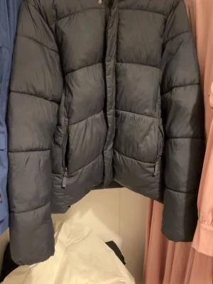 Svart pufferjacka från Dressmann S - Säljer en svart pufferjacka från Dressmann i storlek S. Jackan har en klassisk quiltad look, dragkedja framtill och två sidofickor med dragkedja. Perfekt för kalla dagar och riktigt skön att bära. Materialet är syntet och jackan har lång ärm.