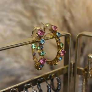 Örhängen guld hoops Caroline Svedbom - Super snygga örhängen i guld med färgade kristaller från Caroline Svedbom, aldrig använd🪽Diametern är 2,5 cm. Passar till alla tillfällen✨Just denna färgkombination finns inte kvar på deras hemsida, ordinarie pris 695kr. Skickar samma dag/dagen efter💞
