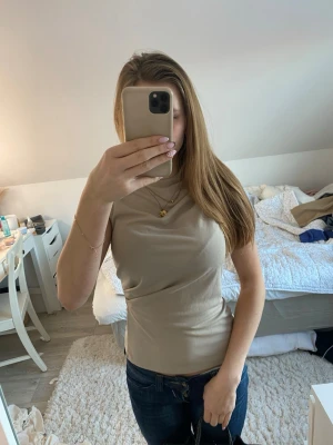 Beige ärmlös topp från Stockh LM - Snygg beige ärmlös topp från Stockh LM i storlek XS. Toppen har en hög hals och dragkedja i sidan för enkel påklädning💕blusen är helt ny med tagg kvar