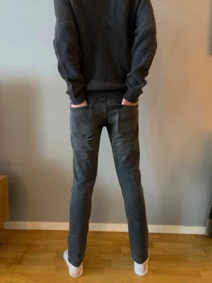 Mörkgrå slim jeans från nudie  - Säljer ett par mörkgrå jeans från nudie  med snyggt tvättad look. Modellen är slim fit med normal midja och raka ben. Klassiska femficksdetaljer och tillverkade i mjukt jeanstyg som sitter skönt hela dagen. Priset ej hugget i sten