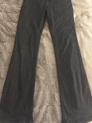 Svarta bootcut jeans  - Säljer ett par svarta bootcut jeans från Kappahl i storlek 170. Jeansen har klassisk femficksdesign, hög midja och är tillverkade i ett mjukt bomullsmaterial med lite stretch. Snygg passform som sitter tajt upptill och släpper ut vid bensluten.