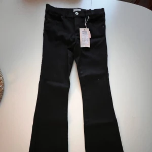 Svarta bootcut jeans från ONLY - Svarta jeans från ONLY i modellen KOOROYAL LIFE REG FLARED. Byxorna har bootcut-snitt med utsvängda ben och är gjorda i svart denim. Klassisk femficksdesign och knappstängning framtill. Perfekta för dig som gillar en trendig siluett. Säljer pga sen retur! Helt nya aldrig andvända