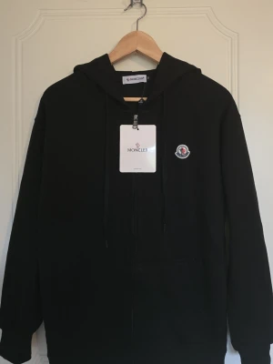 Svart moncler hoodie  - Svart Moncler hoodie, storlek medium hoodien är aldrig använd, priset går att diskuteras 