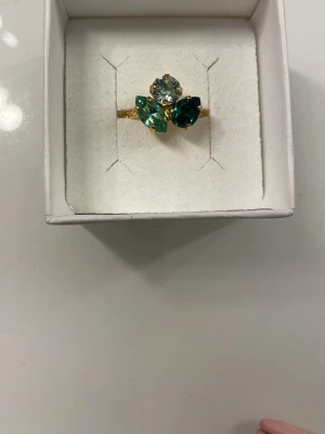 Guld Caroline svedbom ring - Säljer min guldiga Caroline svedbom ring med gröna stenar då jag inte använder den. Den är ungefär aldrig använd och inget fel på den.  Den är även en justerbar ring