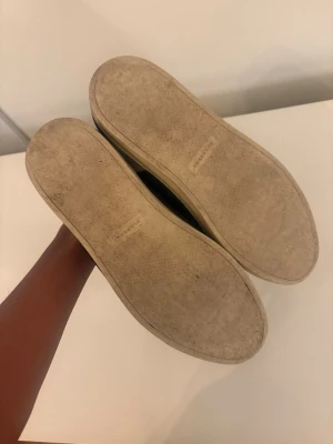 Svarta Burberry sneakers med rutig detalj - Bra skick inga skador passar storlek 41,42 riktigt bra pass form.Snygga svarta sneakers från Burberry med klassisk rutig panel i beige och grått på hälen. Skorna har snörning, platt sula och är tillverkade i skinn och mocka. Perfekt för dig som gillar stilrena och tidlösa sneakers med en twist.ÄKTA