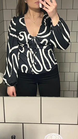 Topp från NA-KD - Fin långärmad topp från NA-KD. - Svart/vit - Tunt material  - Puff axlar - U ringning - Snörning i fram - Resorband längst ner på ärmarna.  Använd 2 gånger, köptes för 349 kr