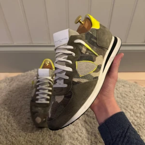 Philippe model sneakers - Tjena! Säljer ett par philippe model sneakers med camouflage print. De är i storlek 41 och mycket bra skicka, se bilderna. Endast skorna medkommer. En liten spricka finns vid det gula som inte syns på bilderna. Kan skicka vid intresse. Hör gärna av er vid frågor och funderingar!🤗