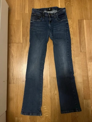 Blå bootcut jeans från LTB, low rise - Säljer ett par blå jeans från LTB i modellen bootcut med låg midja. Klassisk femficksdesign, snygga slitningar shaped vid låren och raka ben som går ut lite retsamt vid ankeln. Tillverkade i mjukt denimtyg som sitter skönt hela dagen.