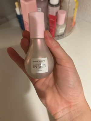 Glow Recipe Watermelon Glow Dew Drops - Glow Recipe Watermelon Glow Niacinamide Dew Drops i en pärlemorskimrande, droppformad flaska med ljusrosa pump och lock. Ger glow och kan användas som highlighter eller primer för extra lyster. Innehåller niacinamid och doftar fräscht av vattenmelon.