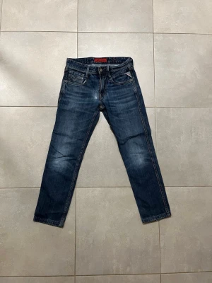 Replay Anbass blå jeans, storlek 29 - Snygga Replay Anbass jeans i mörkblå tvätt med slitningar och klassiska fem fickor. Jeansen har raka ben och låg midja, med Replay-logga på fickan och bak. Perfekta för dig som gillar en avslappnad men stilren look. Waist 29 Length 32, vid snabb affär kan priset diskuteras