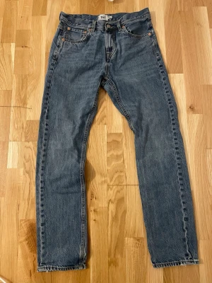Ljusblå raka jeans från 157, W29 L32 - Klassiska blå Straight leg jeans från 157 med raka ben och femficksmodell. Jeansen har normal passform och sitter bekvämt. Tillverkade i slitstarkt denimtyg av bomull. Perfekta för en avslappnad och tidlös look. Jeansen är i mycket bra skick man har en defekt som man kan se på slide 3 då det är ett litet litet hål vid kanten av bakfickan. 