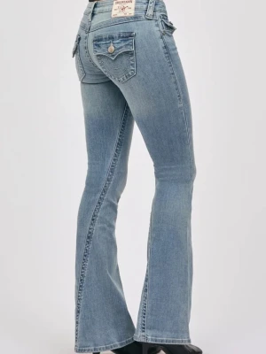  True Religion, Joey Low Rise Flare - Säljer ett par ljusblå bootcut jeans från True Religion med klassiska broderade bakfickor och snygga detaljer. Jeansen är använda 2 ggr. De har varit uppsydda, därav kan man se en linje längst ned. Se bild 4.