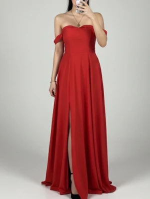 Röd axelbandslös långklänning - Säljer en röd axelbandslös långklänning med offshoulder-detaljer och en snygg slits framtill. Klänningen har en figurnära överdel och ett svepande, utsvängt kjolparti. Perfekt för bal eller festliga tillfällen.