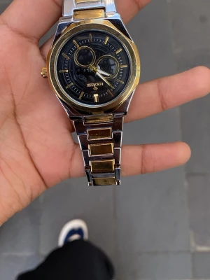 Saudi Watch  - Bilderna visar en armbandsklocka från Locasse i silver och guld, inte en väst. Ingen väst finns att beskriva.