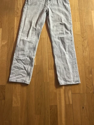 Ljusgrå jeans från GANT - Säljer ett par ljusgrå jeans från GANT med klassisk femficksdesign och raka ben. Jeansen har en snygg tvättad look och är tillverkade i bomull. Perfekta för dig som gillar en stilren och avslappnad vibe.