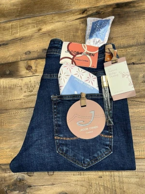 Jacob Cohën mörkblå jeans - Snygga mörkblå jeans från Jacob Cohën med klassisk femficksdesign och kontrastsömmar. Jeansen är tillverkade i högkvalitativt denim med naturlig indigo-färgning och har exklusiva detaljer som märkestaggar och innerfoder med mönster. Perfekta för dig som gillar stilrena och tidlösa jeans.