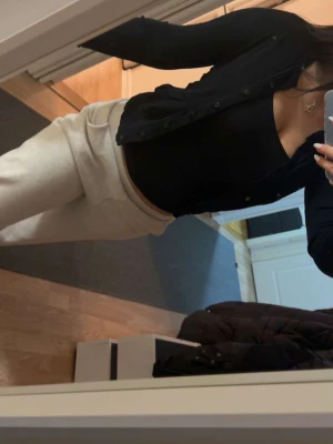 Svart kofta med knappar - Säljer en svart kofta med långa ärmar och knappar framtill. Koftan har en klassisk, slim passform och är perfekt att slänga över en topp. Materialet känns mjukt och stretchigt, vilket gör den skön att bära. Passar dig som gillar stilrena och enkla plagg.