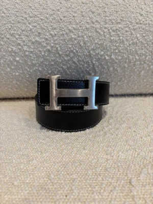 H-Bälte - Ett svart H-bälte perfekt för dig som gillar mode och stil, bältet har ett H med färgen silver och är ett fint märke och ett välkänt märke från Frankrike Paris. Kom dm för eventuella frågor 🧐pris kan diskuteras 💯. 