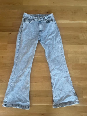 Ljusblå bootcut jeans med hög midja - Säljer ett par ljusblå bootcut jeans med hög midja. Klassisk femficksmodell och snygg tvättad denim. Perfekta för dig som gillar retrovibbar och vill ha ett par jeans som sticker ut lite extra.