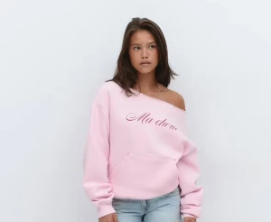 Gina tricot 14+, Rosa offshoulder tröja  med text Stl s - Säljer en ljusrosa tröja med offshoulder-passform och texten 'Ma chérie' framtill. Tröjan har en stor magficka, ribbade muddar och är tillverkad i mjuk bomullsblandning. Perfekt för dig som gillar en chill och trendig look. Använd en gång;)