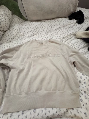 Beige sweatshirt Angelic Divided H&M - Säljer en beige sweatshirt från Divided H&M med broderad text 'ANGELIC' framtill. Tröjan har långärmad passform, ribbade muddar och är gjord i mjuk bomullsmix. Perfekt för chill dagar och enkel att styla med jeans eller leggings.