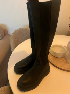 Svarta höga boots  - Säljer ett par svarta höga boots, köpta i början av året men har tyvärr aldrig kommit till användning här hemma. Köpte för 1100kr på Nelly men dom har nu utgått i sortiment! 