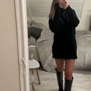 Svart stickad poloklänning - Svart stickad klänning med polokrage alternativt stor tjock tröja. Perfekt att styla med höga boots och eller bälte
