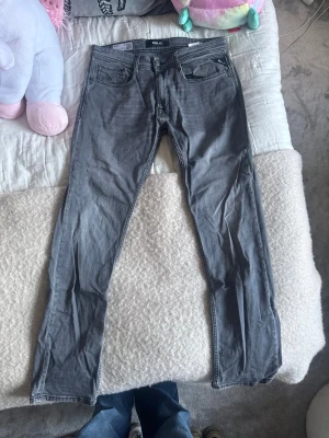 Replay grå jeans, storlek 31 - Snygga grå jeans från Replay, modell Rocco med comfort fit. Klassisk femficksdesign, raka ben och diskreta sömmar. Jeansen har knapp och dragkedja i gylfen samt Replay-logga i midjan. 