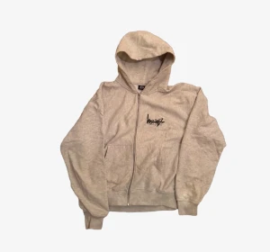 Beige hoodie från Stüssy med tryck - Säljer en beige hoodie från Stüssy med svart logotyptryck både fram och stort på ryggen. Tröjan har huva, dragkedja och två fickor framtill. Materialet är mjuk bomull med fleece på insidan, perfekt för chill dagar. Passformen är normal och ärmarna är långa. Köpt på stussy amsterdam. OBS! Saknar snören