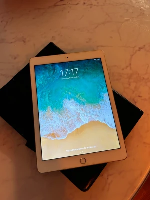 iPad (femte generationen) - Snygg iPad 5th gen med 9,7-tums skärm och Touch ID. Fungerar utmärkt och kör iOS 14.1. Skärmen är fri från större repor, men ramen har mindre slitage. Perfekt för surf, streaming och appar. Levereras med svart fodral. 