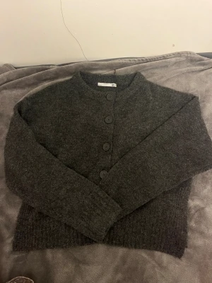 Mörkgrå stickad kofta från 157 - Mysig mörkgrå stickad kofta från 157 i storlek M. Koftan har även en liten slits vid slutet av tröjan!💞denna är aldrig andvänd