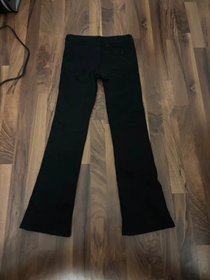 Svarta bootcut jeans från C, stl 152 - Svarta jeans med bootcut passform från märket Cubus i storlek 152. Klassisk femficksmodell med bälteshällor och knappstängning. Materialet är jeans och färgen är helsvart. använt 1 gång.