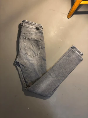 Diesel Slandy grå  - Säljer ett par grå Diesel Slandy jeans. Jeansen har klassisk femficksdesign, stretchigt material och snygga nyanser framtill. Perfekt för dig som gillar en smal siluett och vill ha en cool, urban look.