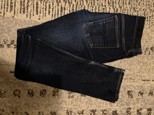 Tiger of Sweden skinny jeans blå - Säljer ett par mörkblå skinny jeans från Tiger of Sweden, modell Severe. Jeansen har klassisk femficksdesign, kontrastsömmar och svart läderpatch vid linningen. Materialet är slitstarkt denim i bomull. Perfekt passform för dig som gillar smal siluett.