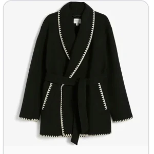 Svart kappa med vit kant - Säljer en snygg svart kappa med vit kantdetalj. Den har en omlottstil med ett bälte i midjan och långa ärmar. Nypris är 900kr mitt pris är 500kr. Köpt för en månad sen använd ca 5-6 gånger. Priset är prutat och klart. Strl Xs men passar S med.