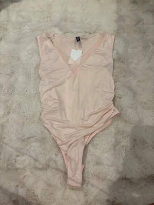Ljusrosa bodysuit från HM - Säljer en ljusrosa bodysuit från HM i storlek M. Bodyn har en djup v-ringning med spetsdetaljer och är ärmlös. Materialet är mjukt och stretchigt. Helt oanvänd. 