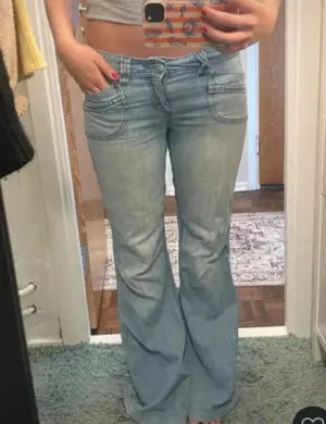 Snygga bootcut jeans från Orsay i ljusblå tvättad denim. Modellen har låg midja, breda benslut och coola detaljer med markerade sömmar och fickor både fram och bak.                                    Midjemått = 38  Innerben = 79  Benöppning = 28  Midjehöjd = 20  Lår = 21 