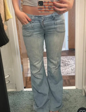 Bootcut jeans i ljusblå denim från Orsay - Snygga bootcut jeans från Orsay i ljusblå tvättad denim. Modellen har låg midja, breda benslut och coola detaljer med markerade sömmar och fickor både fram och bak.                                    Midjemått = 38  Innerben = 79  Benöppning = 28  Midjehöjd = 20  Lår = 21 