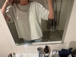 Ljusgrå oversized t-shirttröja - Säljer en ljusgrå oversized t-shirttröja med rund hals och korta ärmar. Tröjan har en chill loose passform och är gjord i mjuk bomull. Snygg detalj med söm vid halsen. Perfekt för en avslappnad look. Aldrig använd