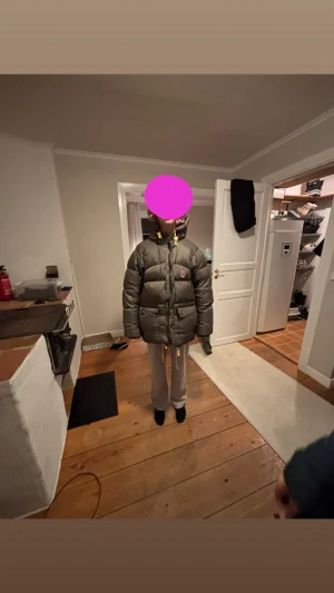 Grön pufferjacka från Fjällräven - Säljer en grön pufferjacka från Fjällräven med hög krage och gula detaljer vid dragkedjan. Jackan har två stora fickor framtill och klassisk Fjällräven-logga på bröstet. Perfekt för kalla dagar och riktigt skön att bära. Storlek xs