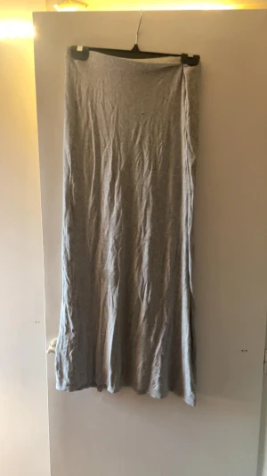 Grå långkjol i mjukt bomullstyg - Säljer en enkel och stilren grå långkjol i mjukt bomullstyg. Kjolen har rak passform och är helt enfärgad utan mönster eller detaljer. Perfekt för dig som gillar minimalistisk stil och vill ha något bekvämt och lätt att matcha. Jag var sytt i den i midjan men kan ta bort det om så