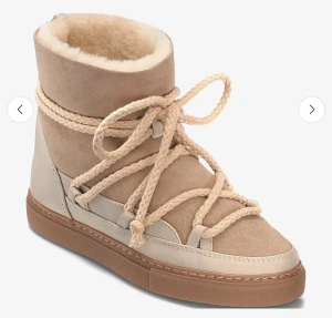 Beige  Inuikii skor  - Säljer ett par snygga beige skor från Inuikii med grova snören och platt sula. Skorna har en rund tå, mjuk päls på insidan och är tillverkade i mocka och skinn. Perfekta för vintern med sin varma och trendiga look.