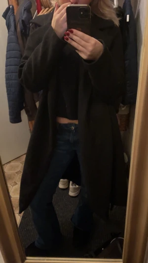 Svart lång kappa med krage - Säljer en svart, stilren och lång kappa med klassisk krage. Jackan har en rak passform och är perfekt för dig som gillar en enkel och clean look. Materialet känns mjukt och värmande, perfekt för kyliga dagar. 