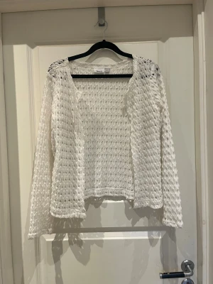 Vit spetskofta från Viveca N XS - Säljer en vit, långärmad kofta från Viveca N i storlek XS. Aldrig använd. Koftan är stickad med ett luftigt spetsmönster och har knappar framtill. Perfekt för dig som gillar en feminin och chill stil med snygga detaljer.