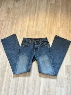 Blå raka jeans från ONLY, storlek 28 - Säljer ett par klassiska blå jeans från ONLY. Jeansen har rak/flare passform, normal midja och fem fickor. Tillverkade i 100% bomull för en autentisk jeanskänsla. Snygg tvätt med lätt slitning framtill och bak, perfekta till sneakers eller boots.