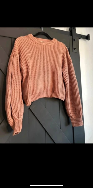  stickad tröja i rosa - Säljer en stickad tröja i en snygg rosa ton. Tröjan har ribbad struktur, rund halsringning och långa, lite puffiga ärmar.