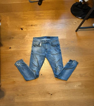 Blå slim jeans med slitningar - Säljer ett par blå slim jeans med slitna detaljer på knän och benslut. Jeansen har klassisk femficksdesign och är tillverkade i stretchig denim för en slimmad passform. Perfekta för dig som gillar en avslappnad och trendig look.