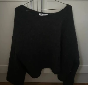 Svart croppad stickad tröja Zara - Svart stickad tröja från Zara med croppad passform och bred halsringning. Tröjan har lång ärm och är perfekt för dig som gillar en chill och lite oversized vibe. Mjuk och fluffig känsla, enkel att matcha med jeans eller kjol. Obs lånad bild ifrån köparen 
