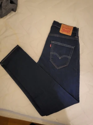 Levi's 520 mörkblå jeans w28 L32 - Säljer ett par Levi's 520 jeans i mörkblå tvätt med klassisk femficksdesign och kontrastsömmar. Modellen har rak passform och normal midja. Materialet är slitstarkt jeans och bakfickorna har den ikoniska Levi's-stilen med läderpatch i midjan.