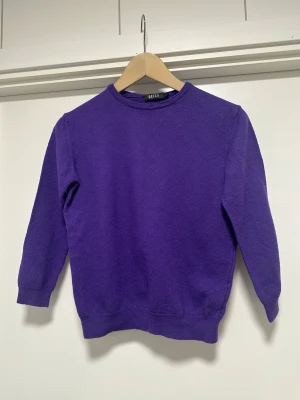 Stickad tröja, 100% merinoull  - Fin stickad lila tröja från REISS i storlek M. Trekvartsärm och rundad hals. 100% merinoull, så bra naturmaterial som håller värmen bra samtidigt som den andas.   Hämtas i Stockholm eller skickas mot porto. 